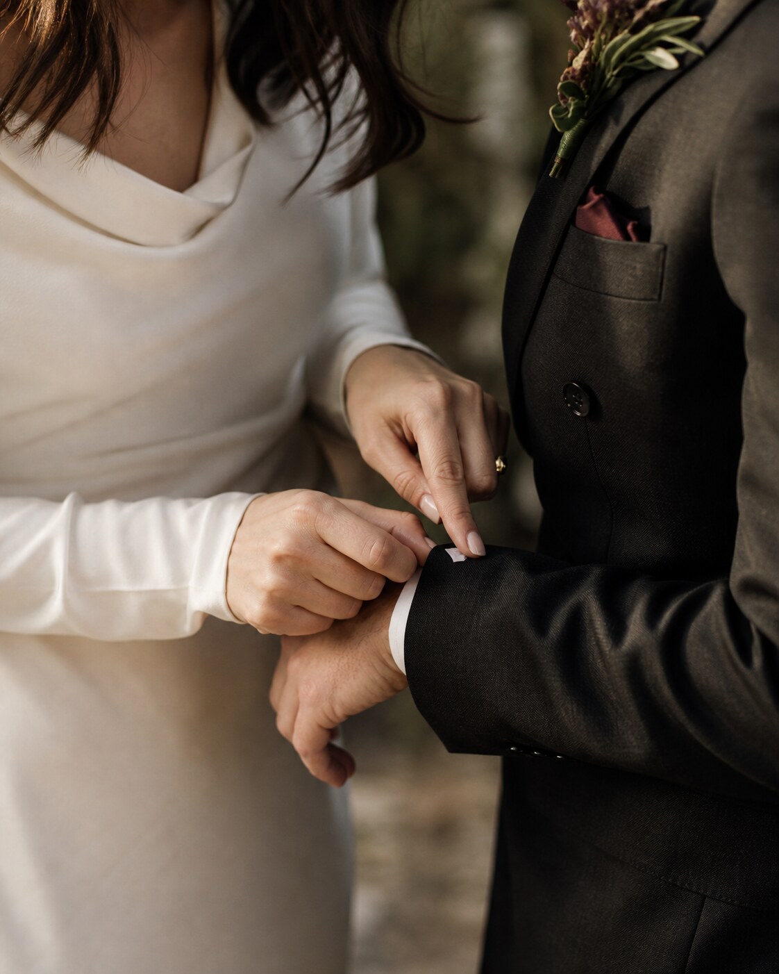One partner brushes a piece of confetti from the other’s cuff